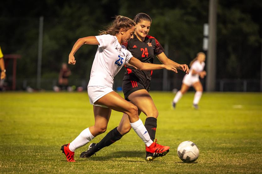 Two soccer players attempt to get the ball
